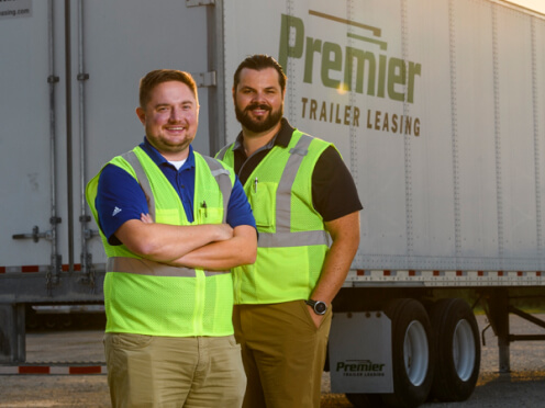 Two Premier Employees smiling in front of a Premier truck